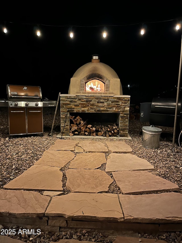 patio at twilight featuring grilling area and a fireplace