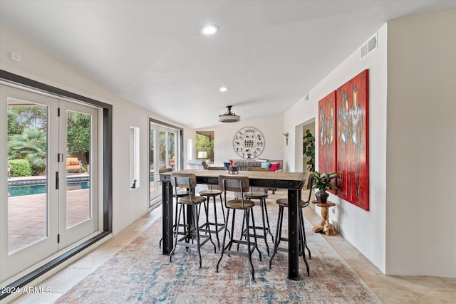 interior space featuring light tile patterned floors, vaulted ceiling, and a breakfast bar area