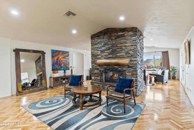 living room featuring a stone fireplace, lofted ceiling, and light parquet floors