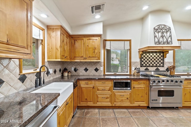 kitchen featuring lofted ceiling, sink, dark stone countertops, appliances with stainless steel finishes, and tasteful backsplash