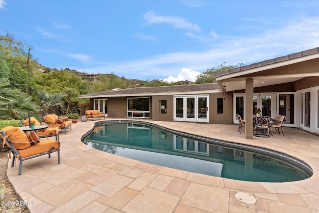 view of pool with a patio area, an outdoor living space, and french doors