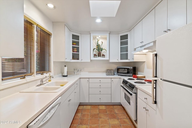 kitchen with white cabinetry, white appliances, sink, and a skylight