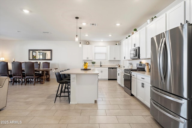 17140 W Running Deer Trl, Surprise, AZ 85387 - kitchen featuring stainless steel appliances, light countertops, a kitchen breakfast bar, decorative light fixtures, and white cabinets