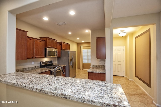 kitchen featuring kitchen peninsula, light stone counters, and stainless steel appliances