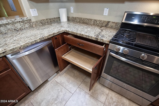 kitchen featuring light tile patterned floors, light stone countertops, and appliances with stainless steel finishes