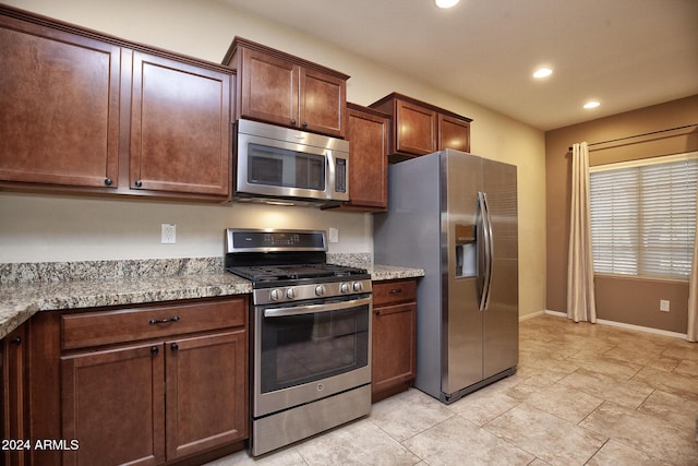 kitchen with light stone counters and appliances with stainless steel finishes