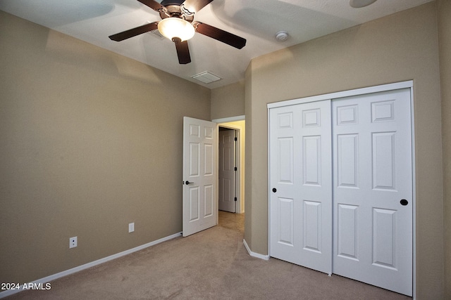 unfurnished bedroom featuring a closet, light colored carpet, and ceiling fan