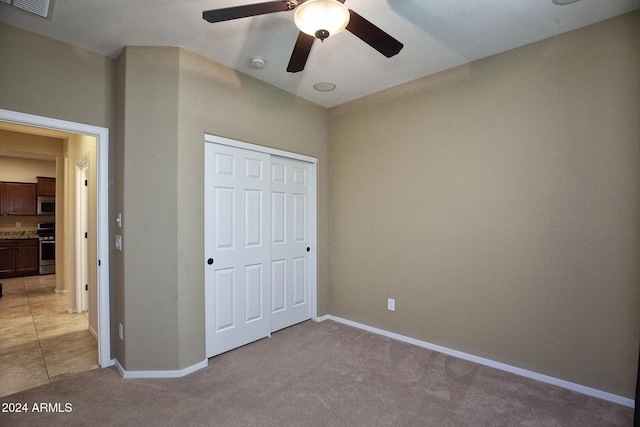 unfurnished bedroom with ceiling fan, a closet, and light carpet