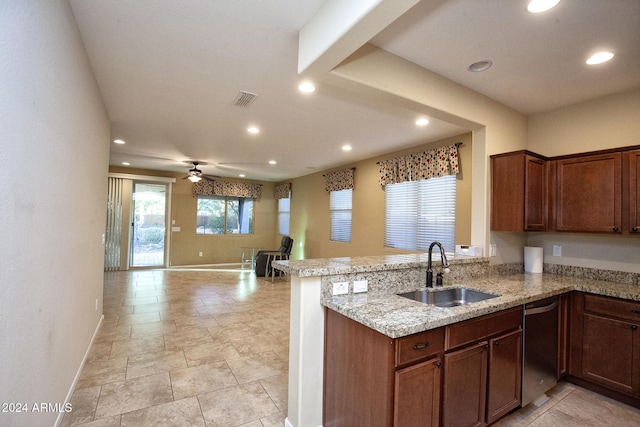 kitchen featuring dishwasher, sink, ceiling fan, light stone counters, and kitchen peninsula