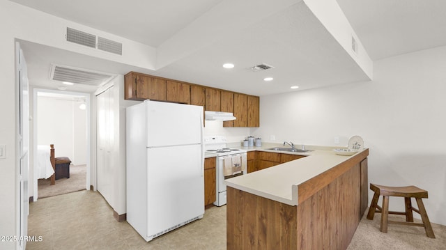 455 N Tegner St Unit 59, Wickenburg, AZ 85390 - kitchen featuring white appliances, under cabinet range hood, a sink, a peninsula, and brown cabinets