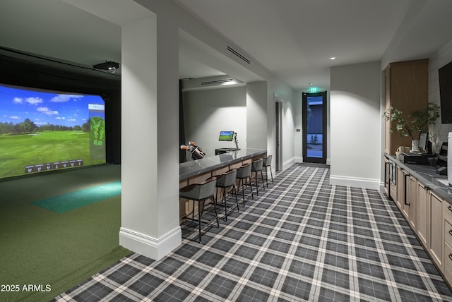 interior space with dark carpet, golf simulator, and light brown cabinetry