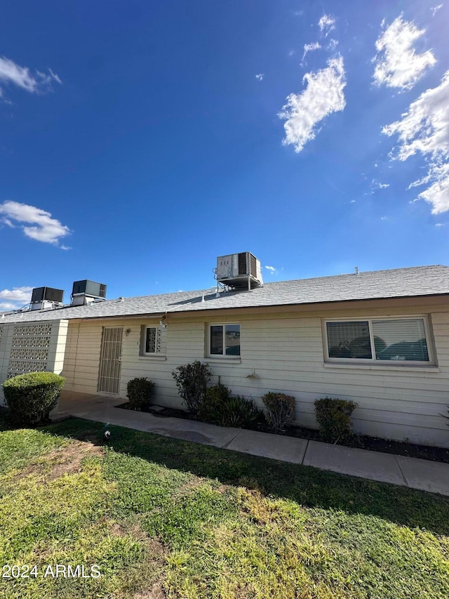 exterior space featuring central AC unit and a front lawn