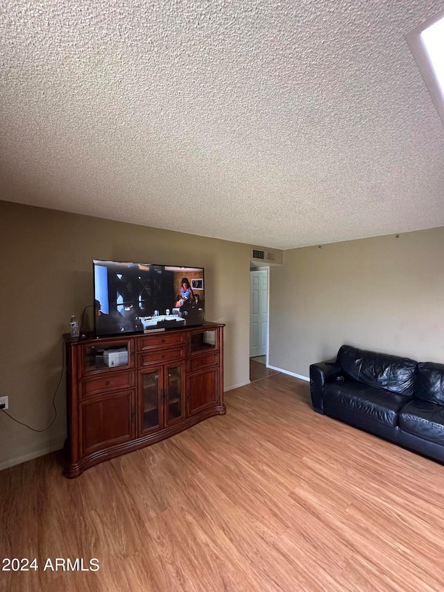 living room with a textured ceiling and light hardwood / wood-style floors