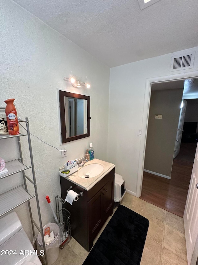 bathroom with hardwood / wood-style floors, a textured ceiling, vanity, and toilet