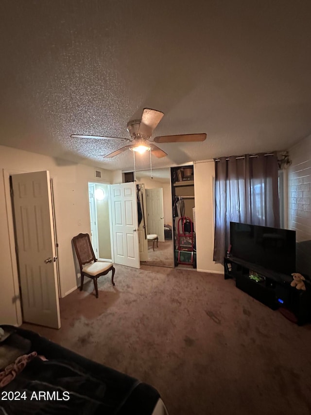 sitting room with ceiling fan, carpet flooring, and a textured ceiling