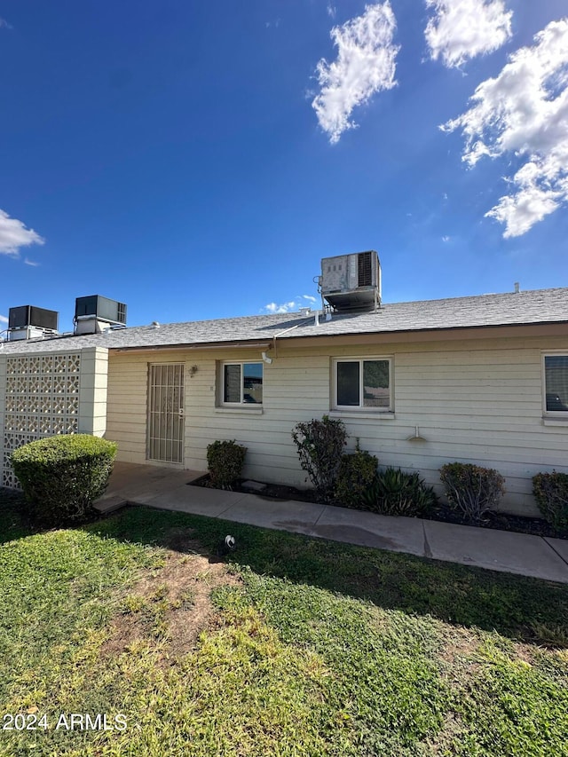 back of property with a lawn and cooling unit