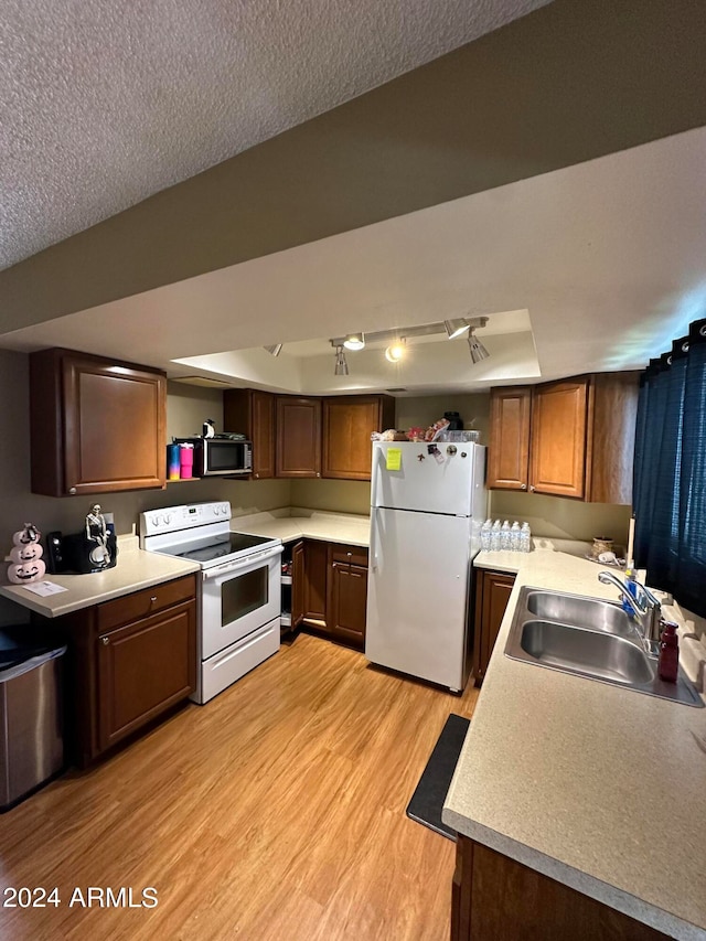 kitchen featuring a textured ceiling, appliances with stainless steel finishes, sink, and light hardwood / wood-style flooring