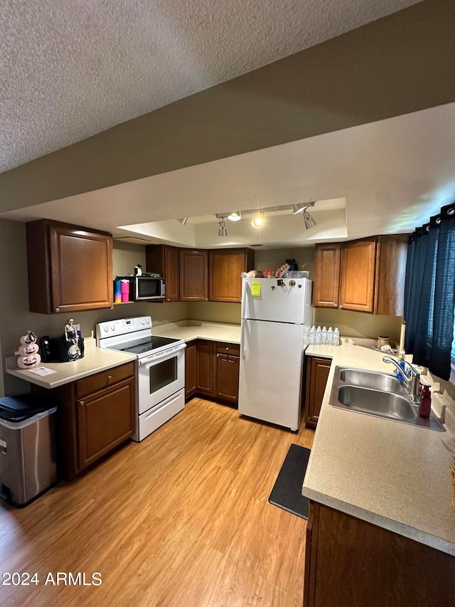 kitchen featuring white appliances, a textured ceiling, light hardwood / wood-style flooring, track lighting, and sink