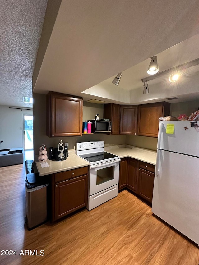 kitchen featuring a textured ceiling, light wood-type flooring, and white appliances