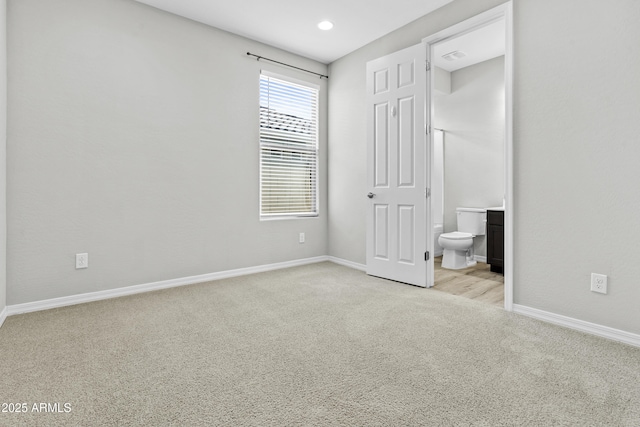 unfurnished bedroom featuring light carpet and connected bathroom