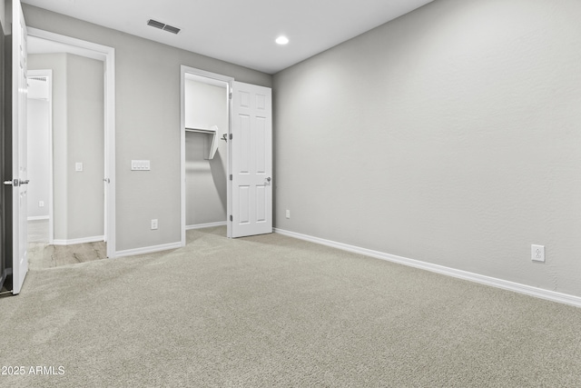 unfurnished bedroom with a spacious closet and light colored carpet