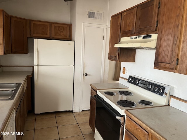 kitchen with light tile patterned floors, white appliances, and sink