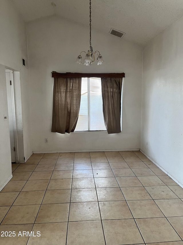 tiled spare room with an inviting chandelier and vaulted ceiling