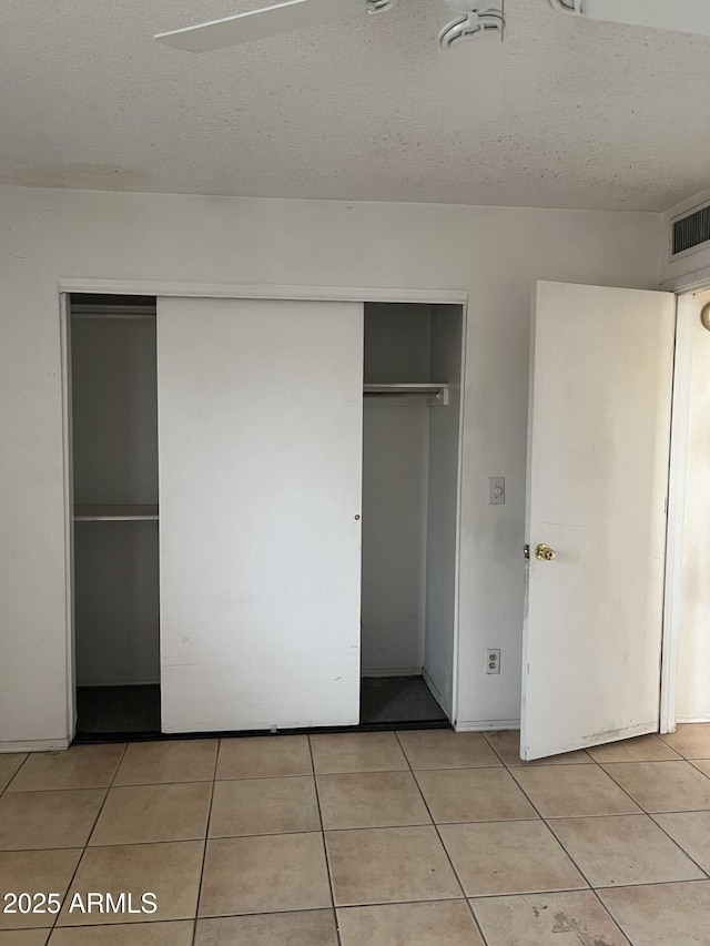 unfurnished bedroom featuring light tile patterned floors, ceiling fan, and a closet