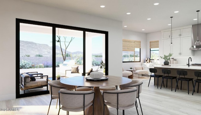 dining space featuring recessed lighting, a healthy amount of sunlight, a mountain view, and light wood finished floors