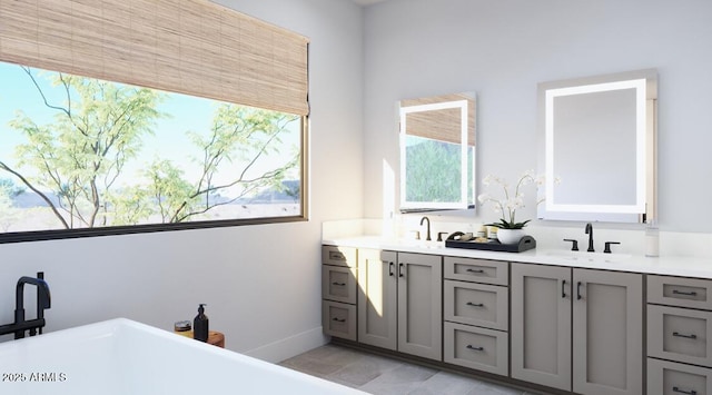 full bathroom with double vanity, a wealth of natural light, a freestanding tub, and a sink