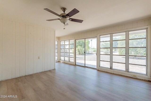 spare room featuring wood-type flooring, ceiling fan, and plenty of natural light