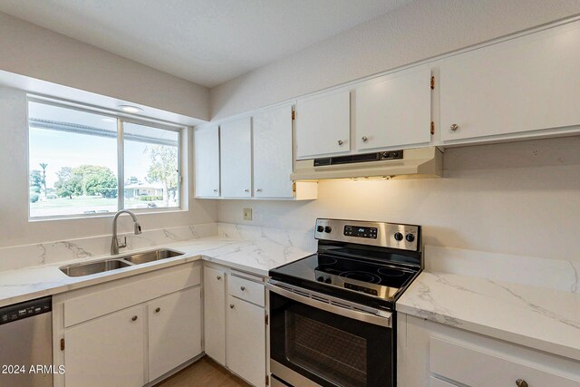 kitchen with white cabinetry, custom exhaust hood, stainless steel appliances, sink, and light stone counters