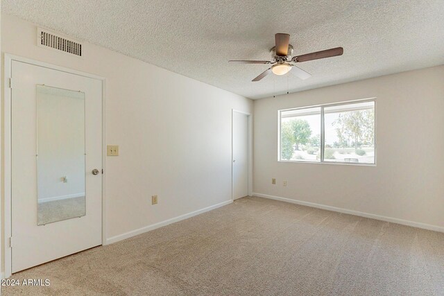 carpeted spare room with a textured ceiling and ceiling fan