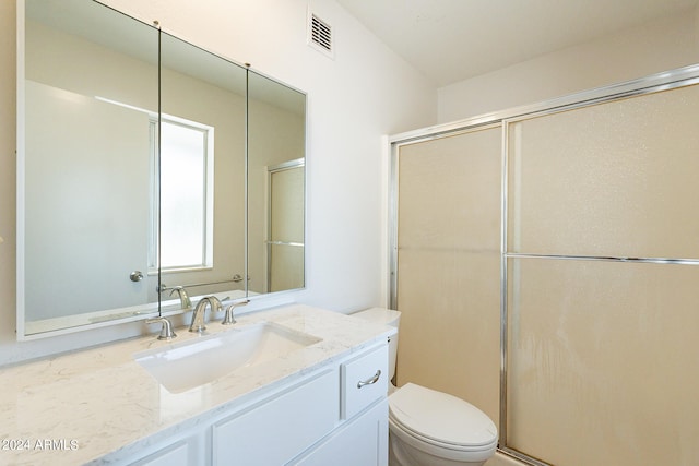 bathroom featuring vanity, walk in shower, and toilet