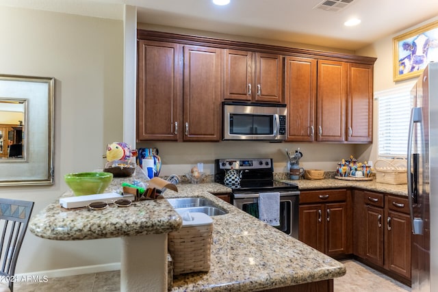 kitchen featuring kitchen peninsula, stainless steel appliances, and light stone countertops