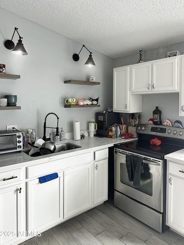 3646 N 67th Ave Unit 64, Phoenix, AZ 85033 - kitchen with stainless steel electric stove, open shelves, a sink, white cabinets, and a textured ceiling