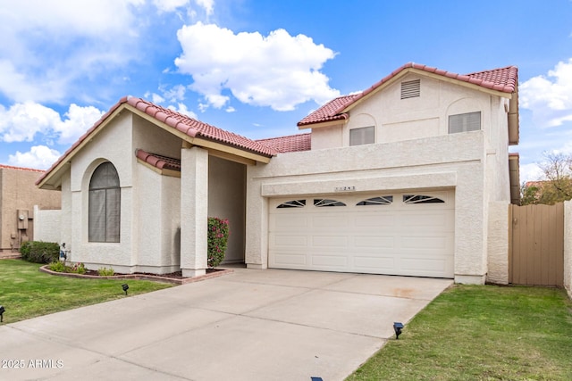 mediterranean / spanish house featuring a tiled roof, stucco siding, fence, a front lawn, and concrete driveway