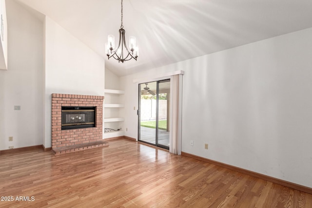 unfurnished living room with light wood finished floors, a notable chandelier, built in shelves, and a fireplace