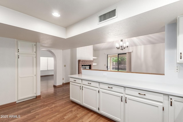 kitchen with white cabinetry, visible vents, light wood finished floors, and a peninsula