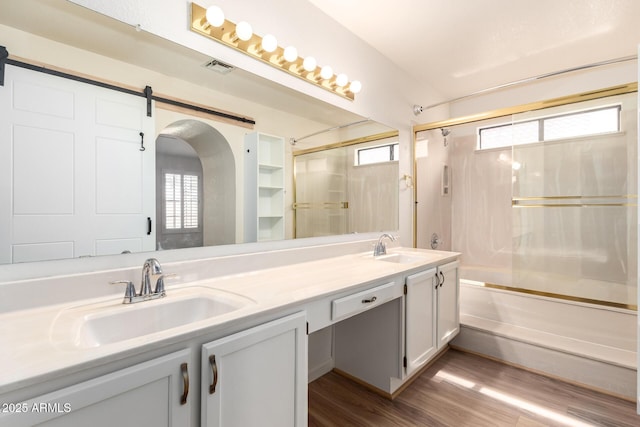 bathroom with a sink, a wealth of natural light, and shower / bath combination with glass door