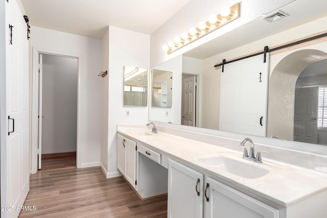 bathroom with double vanity, visible vents, a sink, and wood finished floors