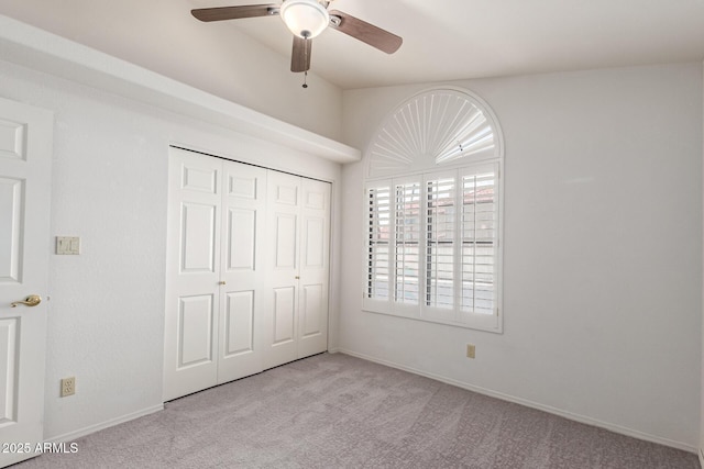 unfurnished bedroom with baseboards, carpet flooring, a closet, and a ceiling fan