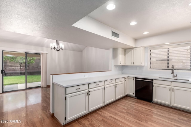 kitchen featuring a peninsula, light countertops, light wood-style floors, dishwasher, and a sink