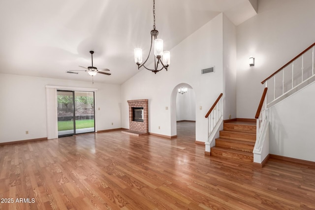 unfurnished living room featuring visible vents, light wood finished floors, stairs, and ceiling fan with notable chandelier