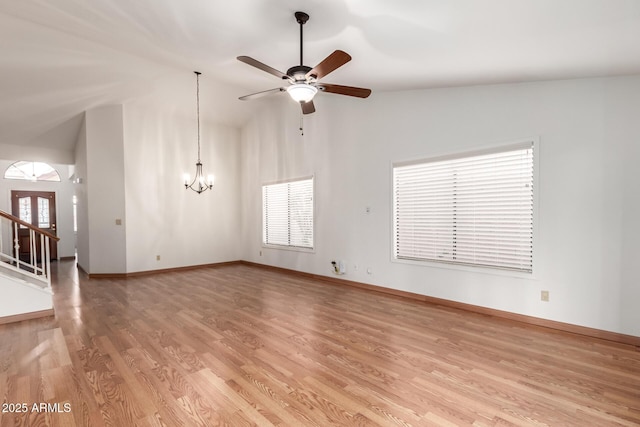 unfurnished living room with baseboards, plenty of natural light, light wood-style floors, and ceiling fan with notable chandelier