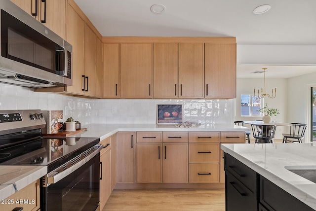 kitchen featuring appliances with stainless steel finishes, pendant lighting, and light brown cabinets