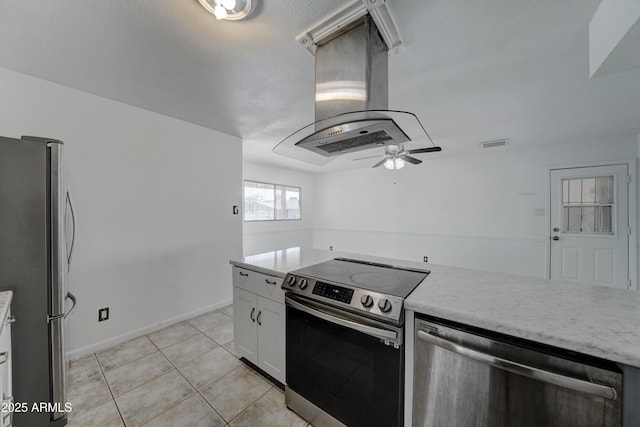 kitchen featuring light tile patterned floors, ceiling fan, appliances with stainless steel finishes, white cabinetry, and island exhaust hood