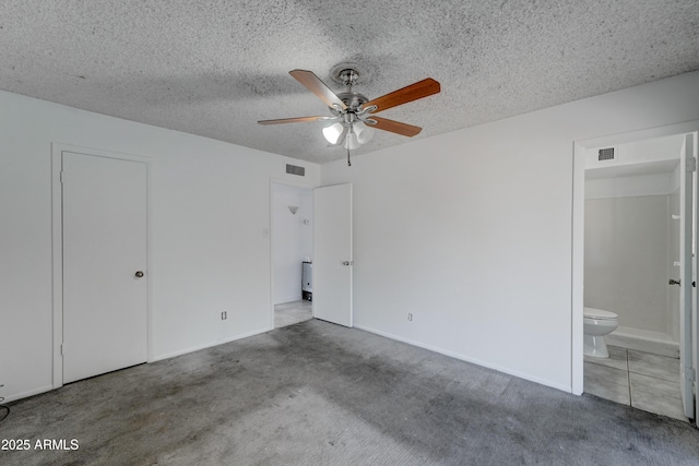 unfurnished bedroom with ensuite bathroom, a textured ceiling, and carpet