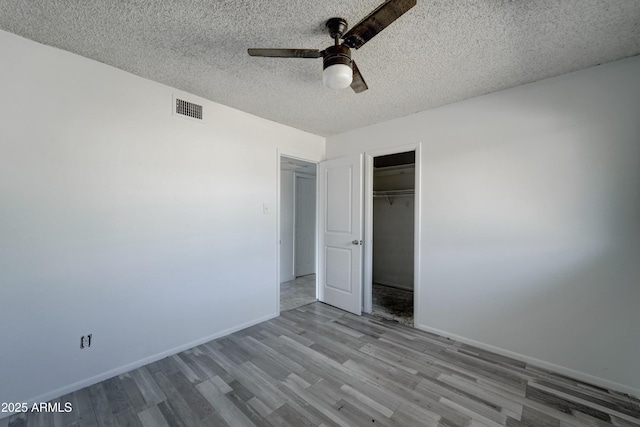 unfurnished bedroom with ceiling fan, a closet, a textured ceiling, and light wood-type flooring