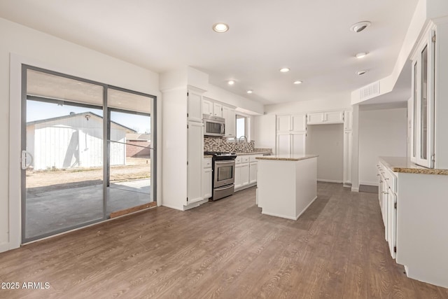 kitchen with decorative backsplash, white cabinets, a center island, and stainless steel appliances